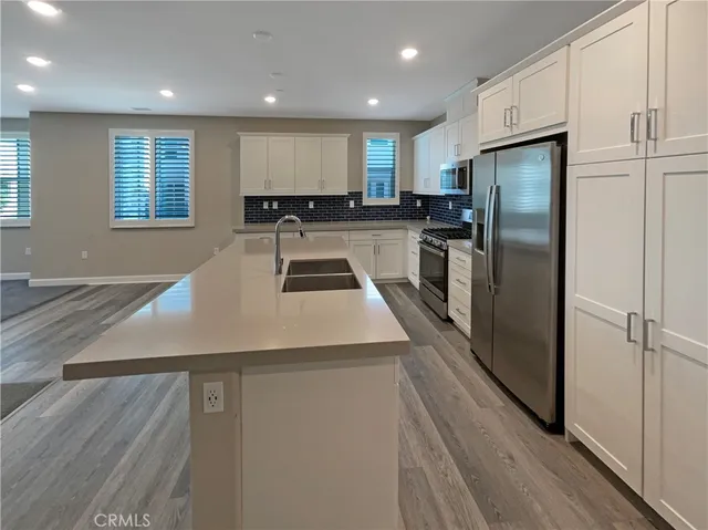 a large kitchen with stainless steel appliances granite countertop a stove a sink and a refrigerator