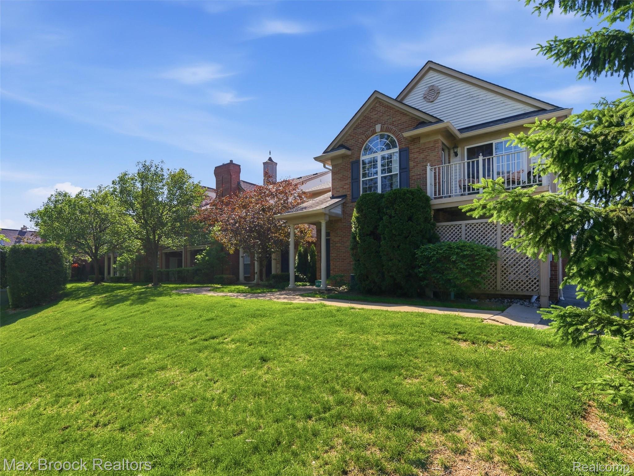 3562 Tremonte Circle Rochester, MI 48306 - Photo 2 of 33 Brick and siding exterior featuring a prominent arched window with shutters, an upper-level balcony with white railings, and a covered entry