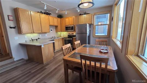 a kitchen with stainless steel appliances granite countertop a table chairs refrigerator and microwave