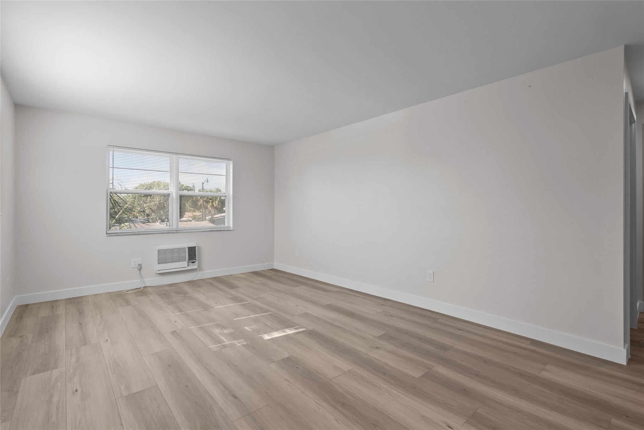 1150 East Sample Road, Unit 202 Pompano Beach, FL 33064 - Photo 5 of 20 wooden floor in an empty room with a window