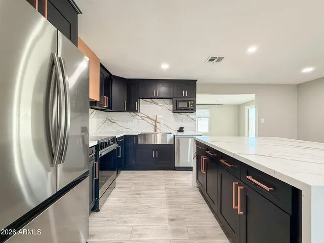 a large kitchen with stainless steel appliances a sink counter space and a window
