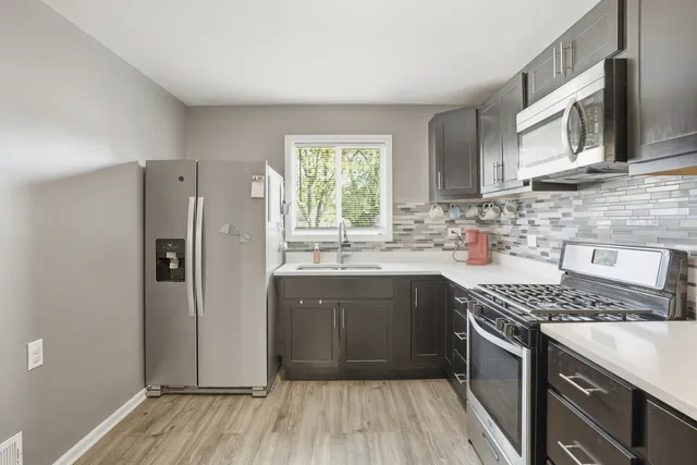 a kitchen with stainless steel appliances granite countertop a refrigerator a sink dishwasher a stove with wooden cabinets and floor