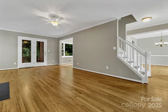 a view of an empty room with wooden floor and fan