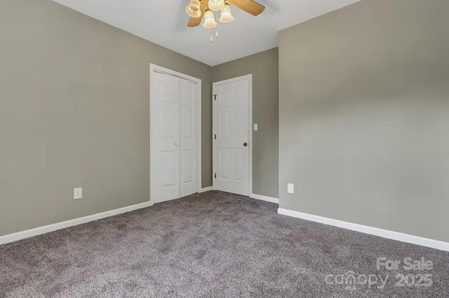 a view of an empty room and a chandelier fan