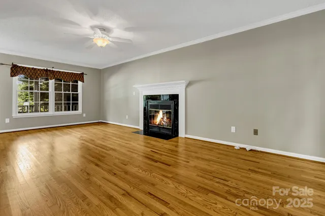 a view of an empty room with a window and wooden floor