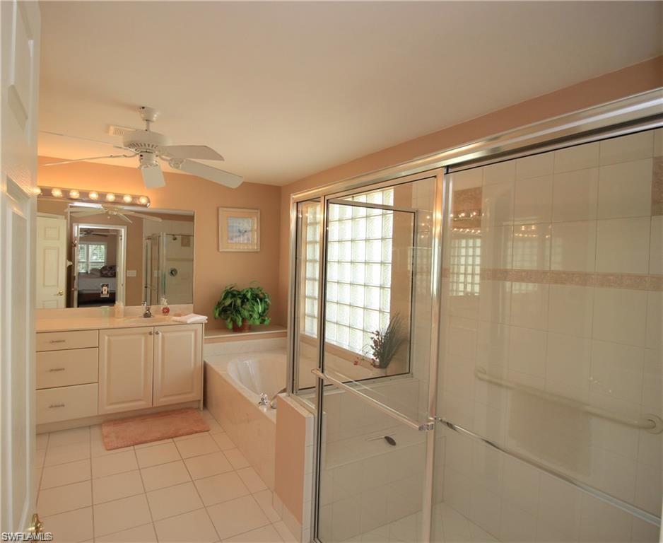 2322 Butterfly Palm Drive Naples, FL 34119 - Photo 19 of 32 a large bathroom with a large mirror vanity and bathtub