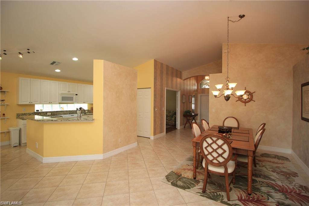 2322 Butterfly Palm Drive Naples, FL 34119 - Photo 5 of 32 a view of a dining room and kitchen with furniture wooden floor and a chandelier
