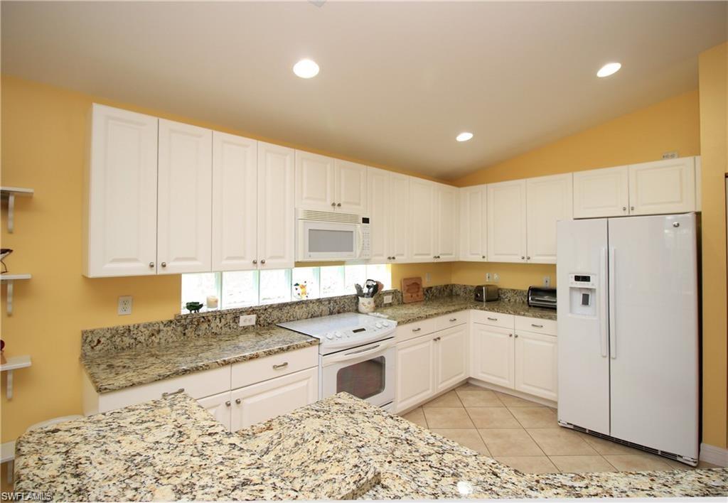 2322 Butterfly Palm Drive Naples, FL 34119 - Photo 6 of 32 a kitchen with white cabinets and white appliances
