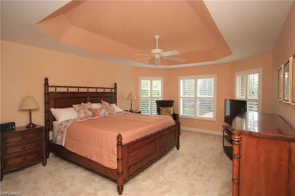 2322 Butterfly Palm Drive Naples, FL 34119 - Photo 10 of 32 a large bed sitting in a bedroom next to a window with pc on the table