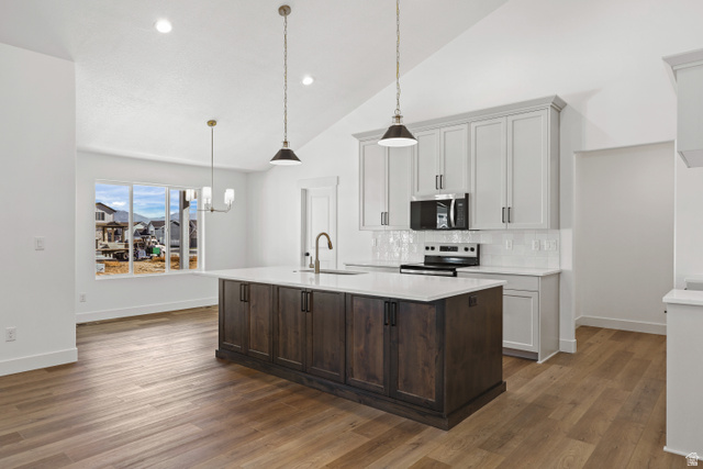 1139 South 4475 West West Point, UT 84015 - Photo 8 of 33 Kitchen with a kitchen island with sink, stainless steel appliances, hanging light fixtures, dark brown cabinetry, and tasteful backsplash