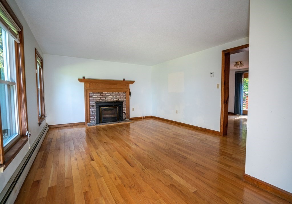 367 Bay Road Amherst, MA 01002 - Photo 7 of 27 an empty room with wooden floor fireplace and windows