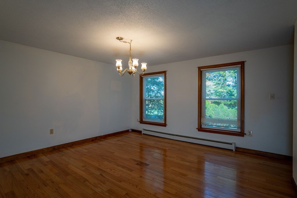 367 Bay Road Amherst, MA 01002 - Photo 8 of 27 an empty room with wooden floor chandelier and windows