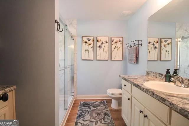 a bathroom with a granite countertop sink a toilet and a mirror