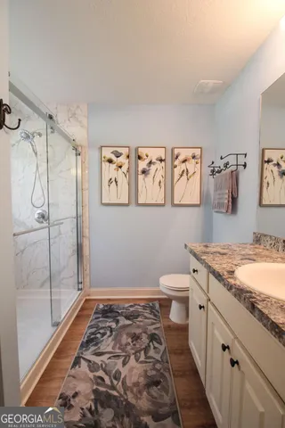 a bathroom with a granite countertop sink toilet and shower