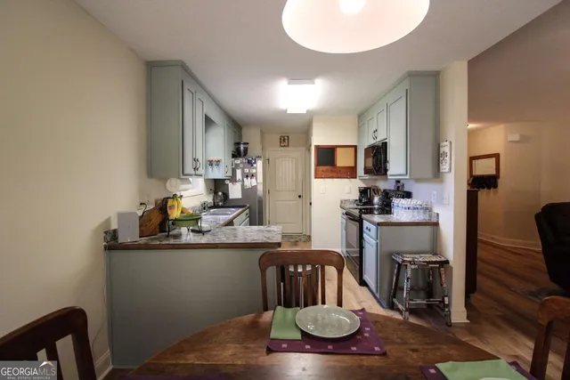a kitchen with sink refrigerator dining table and chairs