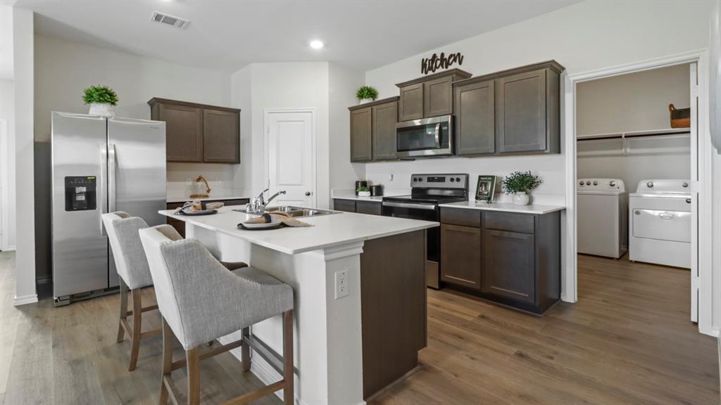 636 Dunham Road Nevada, TX 75173 - Photo 17 of 31 Contemporary kitchen featuring dark wood cabinetry, light countertops, a stainless steel refrigerator, and wood-finish flooring