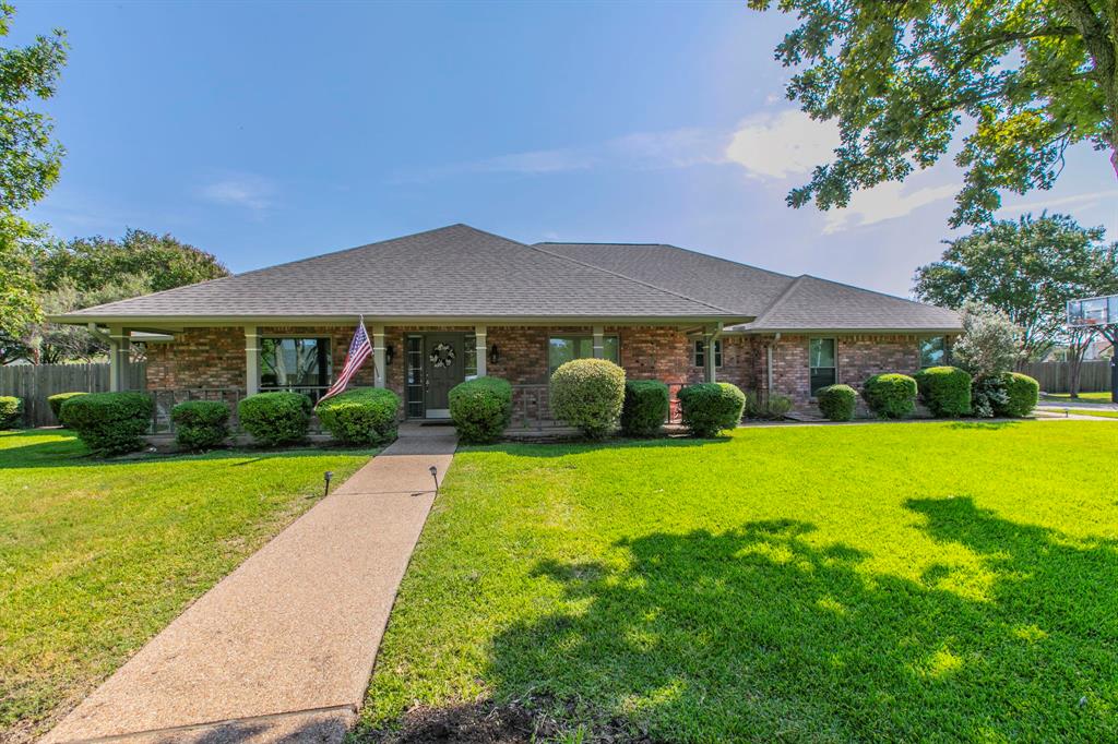 View of front of property featuring a shingled roof, covered porch, and brick siding