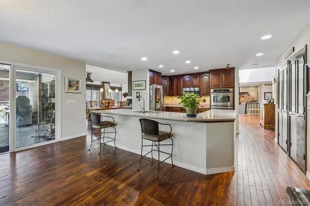 a kitchen with stainless steel appliances kitchen island granite countertop wooden floors and cabinets