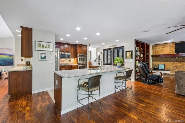a living room with stainless steel appliances granite countertop furniture wooden floor and a kitchen view
