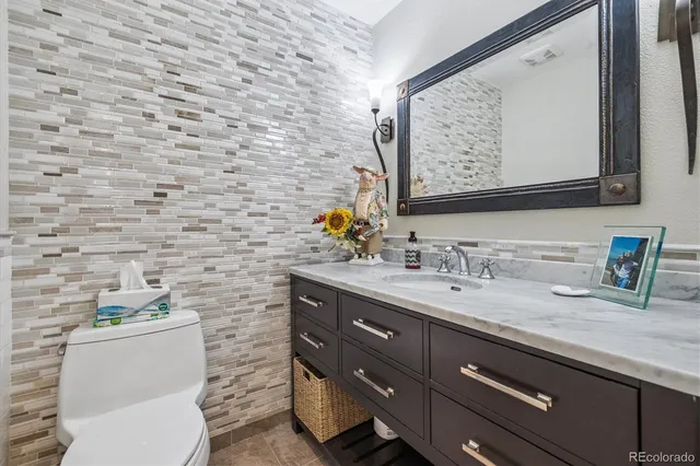 a bathroom with a granite countertop toilet sink and mirror