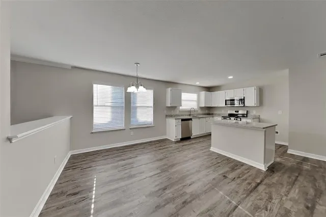 a large white kitchen with kitchen island a sink stainless steel appliances and cabinets