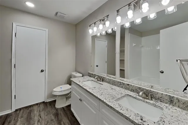 a bathroom with a granite countertop double vanity sink a mirror and a shower