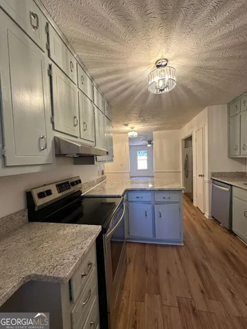 a kitchen with granite countertop a stove cabinets and wooden floor