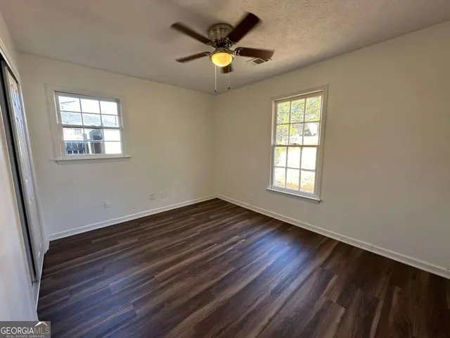 a view of an empty room with window and wooden floor