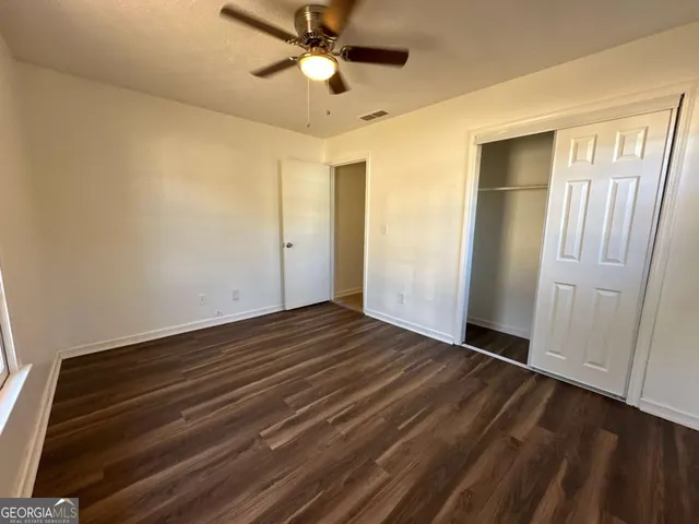 a view of empty room with wooden floor and fan
