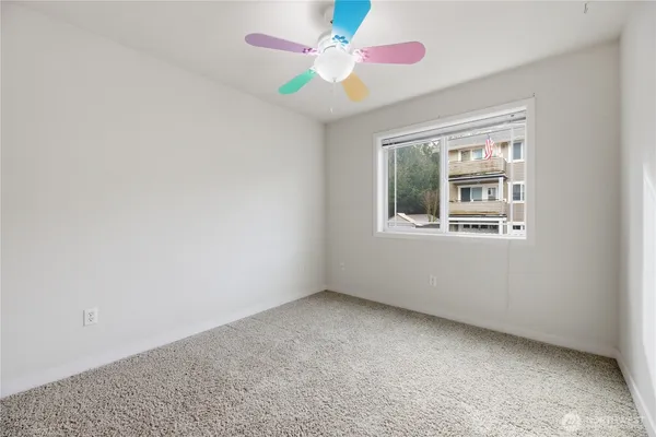 an empty room with a window and a fan