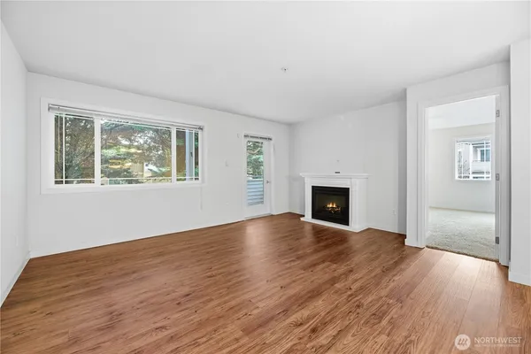 an empty room with wooden floor fireplace and windows
