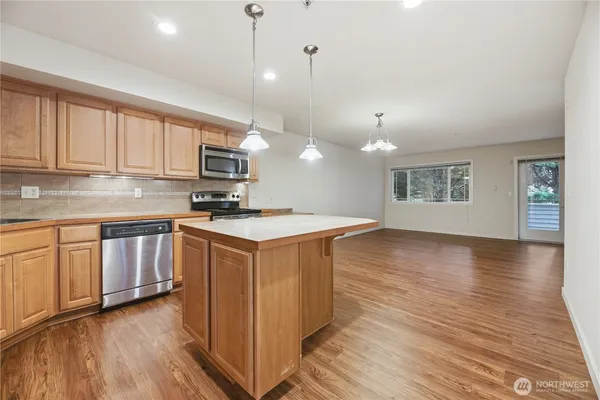 a kitchen with granite countertop a stove a sink dishwasher and a microwave oven with wooden floor