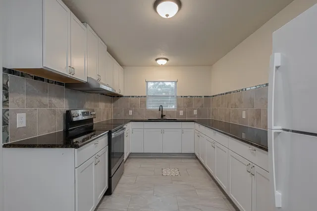 a kitchen with granite countertop white cabinets and stainless steel appliances