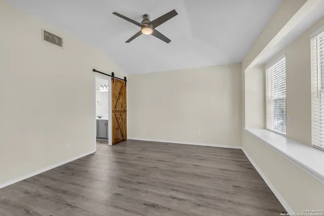 a view of empty room with wooden floor and ceiling fan