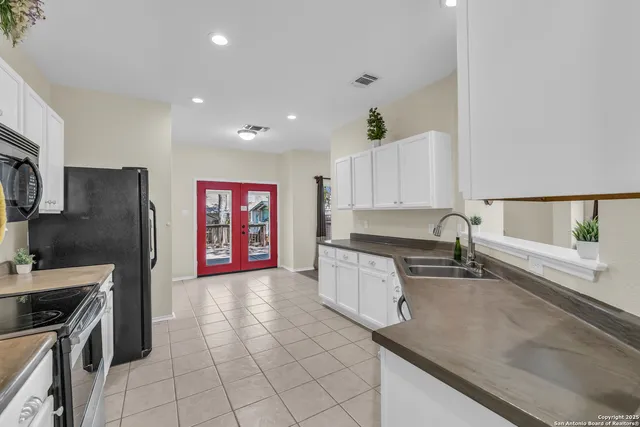 a kitchen with granite countertop a stove a sink and a refrigerator