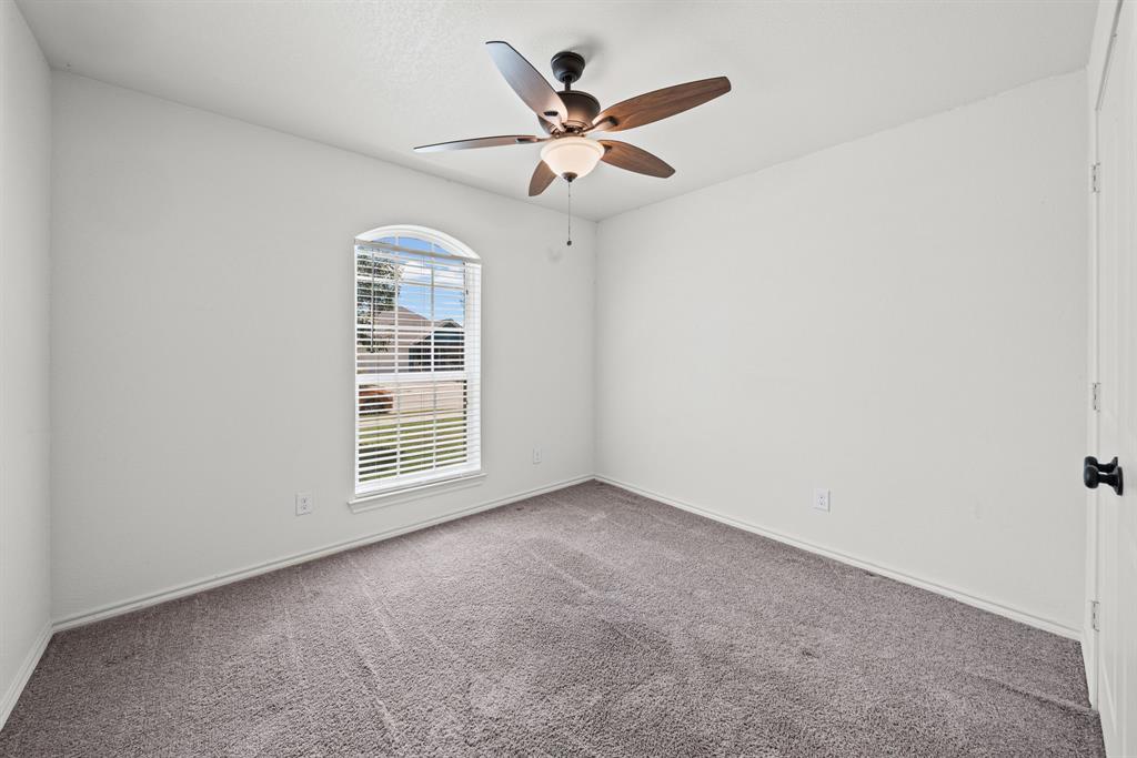 229 Firefly Drive Springtown, TX 76082 - Photo 21 of 33 Neutral-toned room featuring a large arched window with horizontal blinds, a ceiling fan with light fixture, and plush carpet flooring