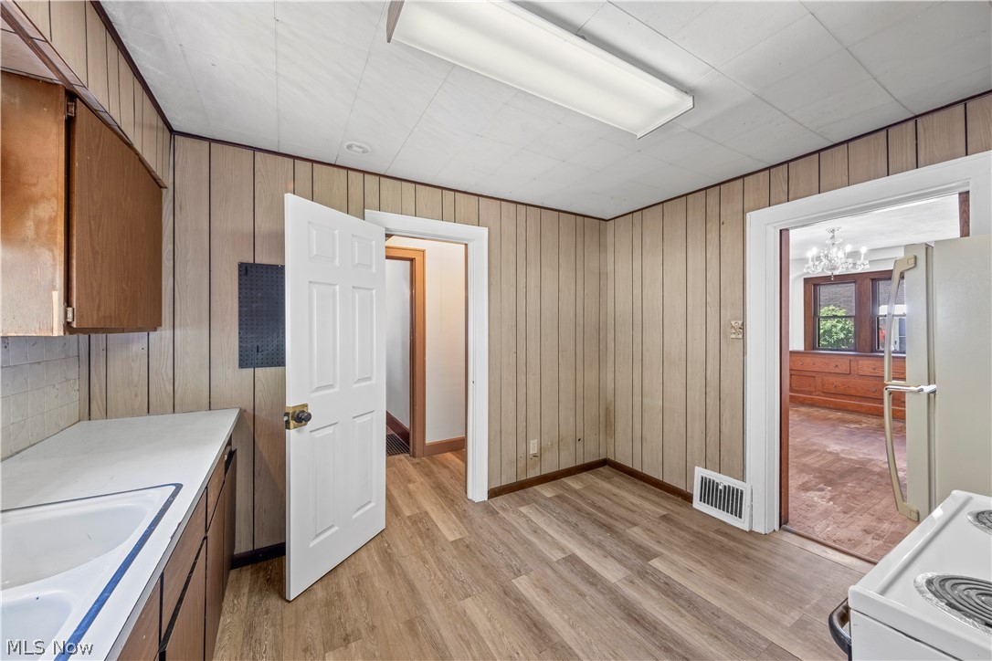 317 Ruckel Road Akron, OH 44305 - Photo 20 of 30 Kitchen featuring stove, wood walls, light wood-type flooring, and white refrigerator