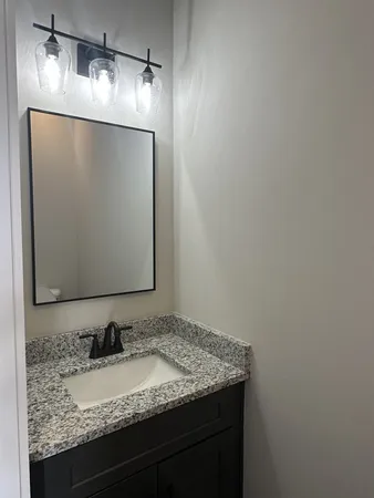 a bathroom with a granite countertop sink and a mirror