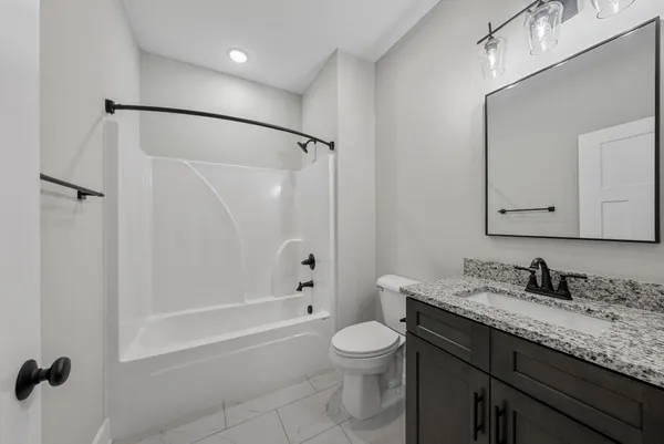 a bathroom with a granite countertop sink a toilet and shower