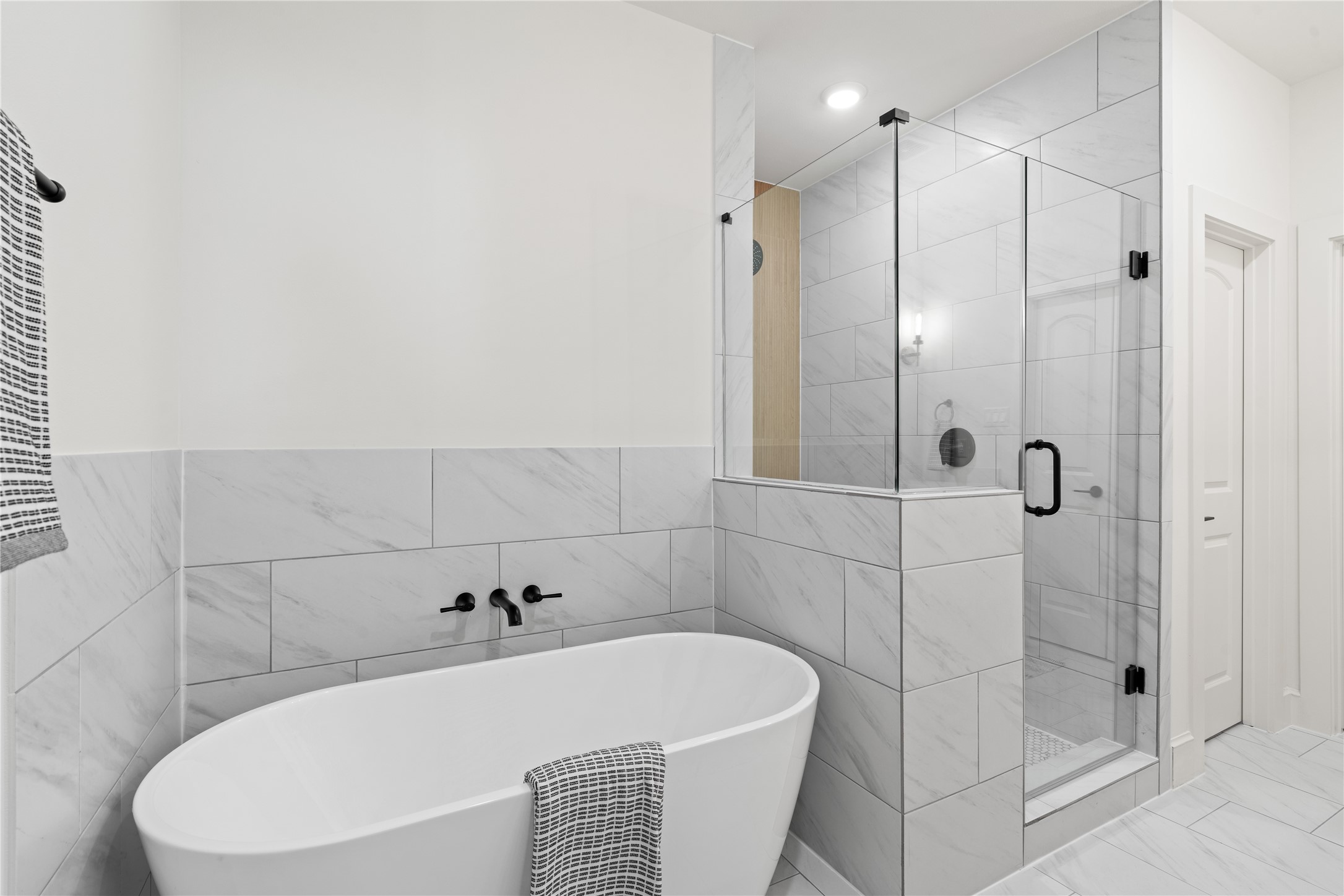 1614 Ojeman Road, Unit C Houston, TX 77055 - Photo 38 of 48 Sleek freestanding bathtub and a spacious glass-enclosed shower. The white and gray tile work enhances the clean, contemporary aesthetic.