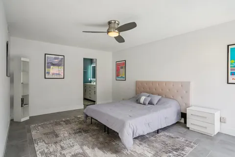 a bedroom with a large bed and ceiling fan