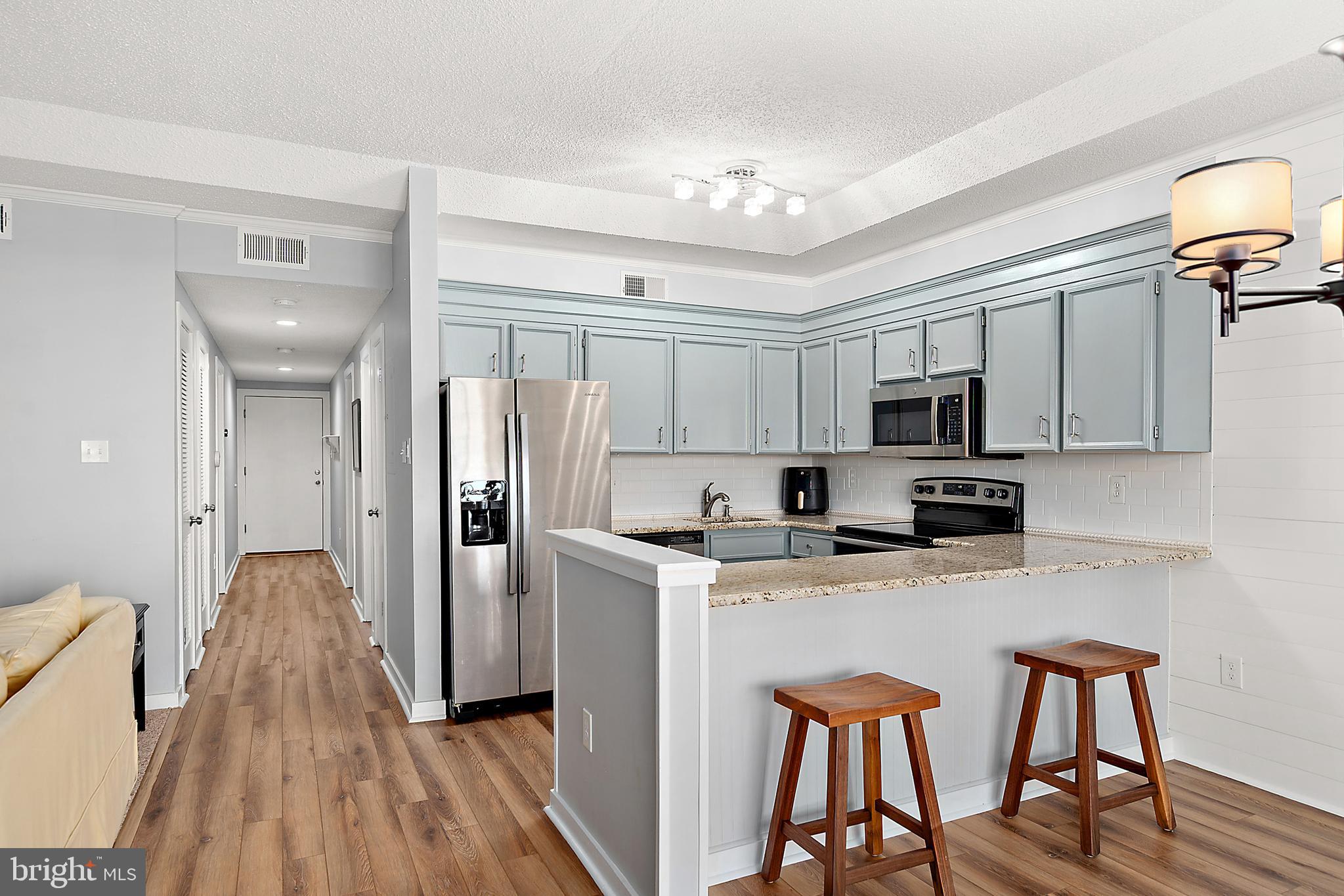 119 Old Landing Road, Unit 302B Ocean City, MD 21842 - Photo 28 of 46 a kitchen with stainless steel appliances granite countertop a refrigerator a stove top oven a sink dishwasher and white cabinets with wooden floor