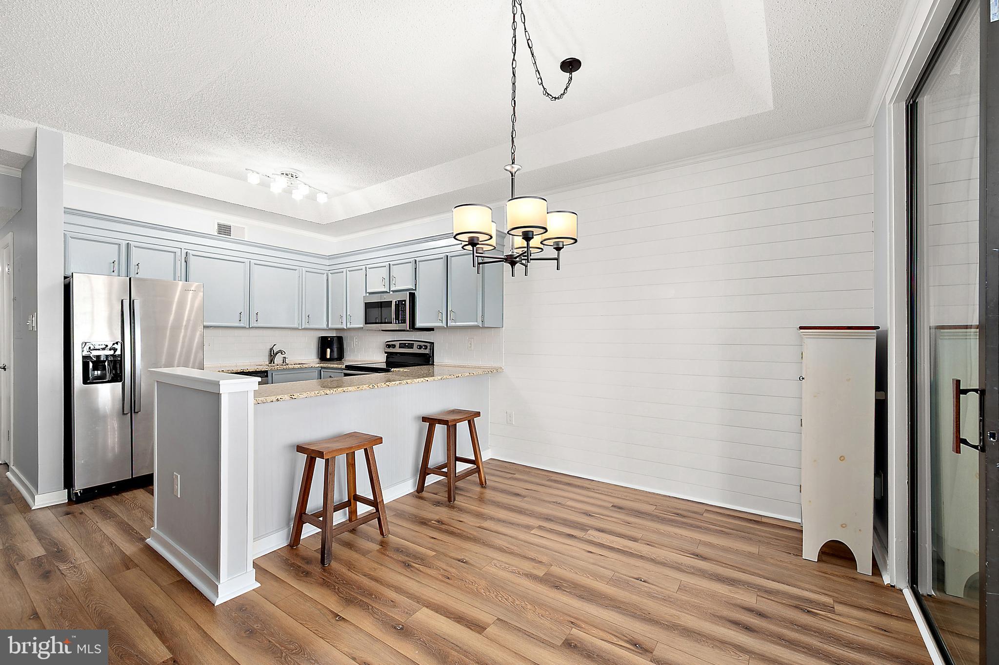 119 Old Landing Road, Unit 302B Ocean City, MD 21842 - Photo 29 of 46 a kitchen with stainless steel appliances granite countertop a refrigerator a sink dishwasher a stove and white cabinets with wooden floor