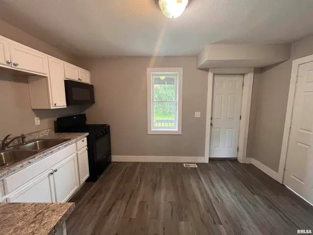 a kitchen with wooden floors and black appliances