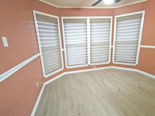 a view of an empty room with a window and wooden floor