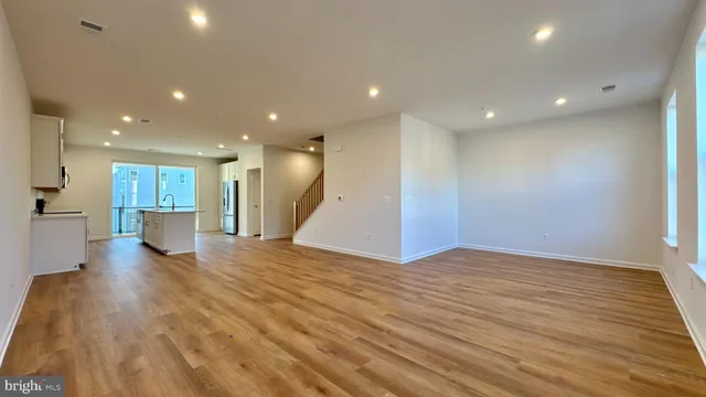 a view of a big room with wooden floor and a kitchen