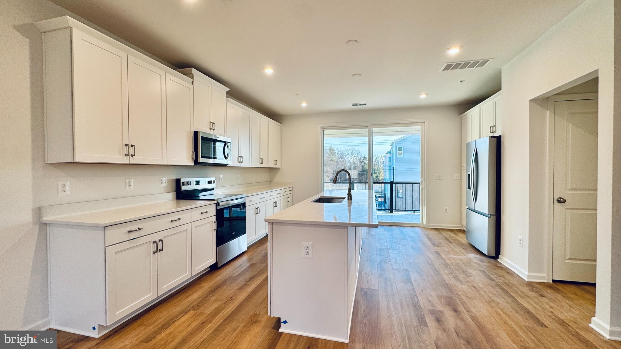 2623 River Birch Road Herndon, VA 20171 - Photo 6 of 12 a large kitchen with stainless steel appliances granite countertop a refrigerator a sink dishwasher a stove and white countertops with wooden floor