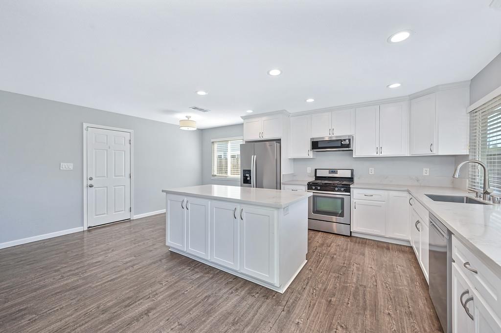 8037 Ruthwood Way Orangevale, CA 95662 - Photo 10 of 37 a kitchen with stainless steel appliances granite countertop a stove top oven a sink dishwasher and a refrigerator with wooden floor