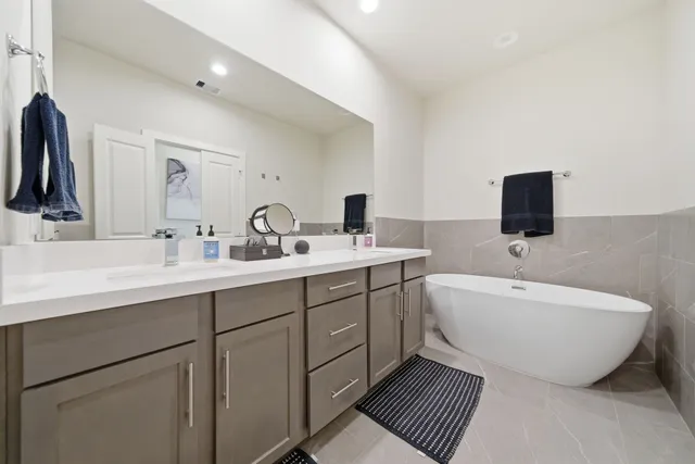 a spacious bathroom with a double vanity sink a mirror and a bathtub