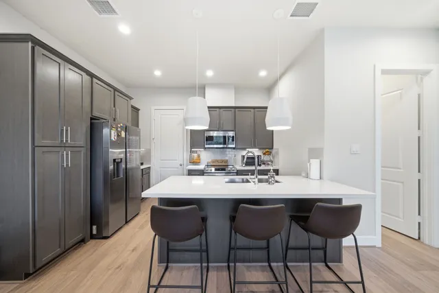 a kitchen with stainless steel appliances granite countertop a table chairs refrigerator and sink